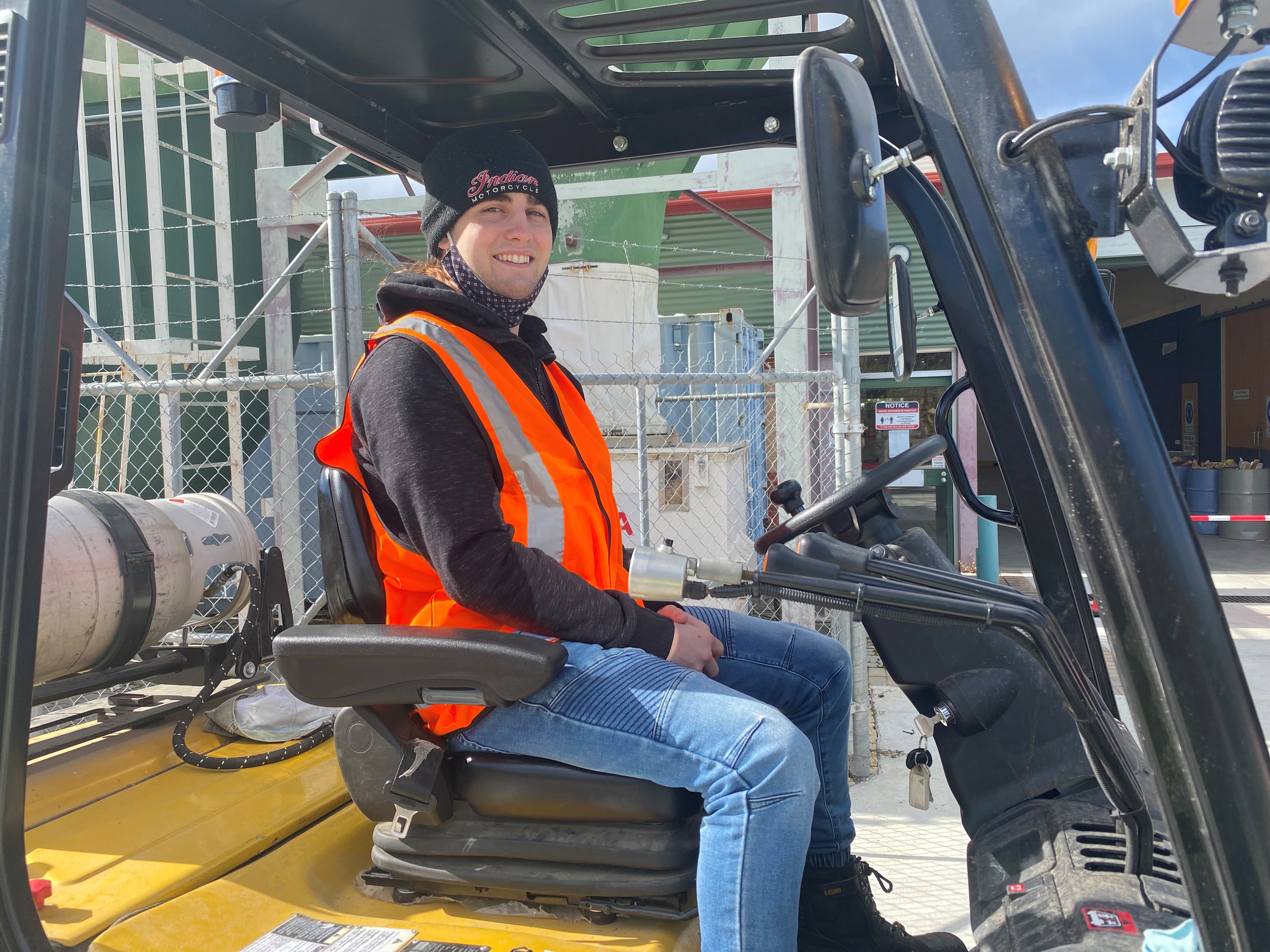 Student posing for a photo on a forklift