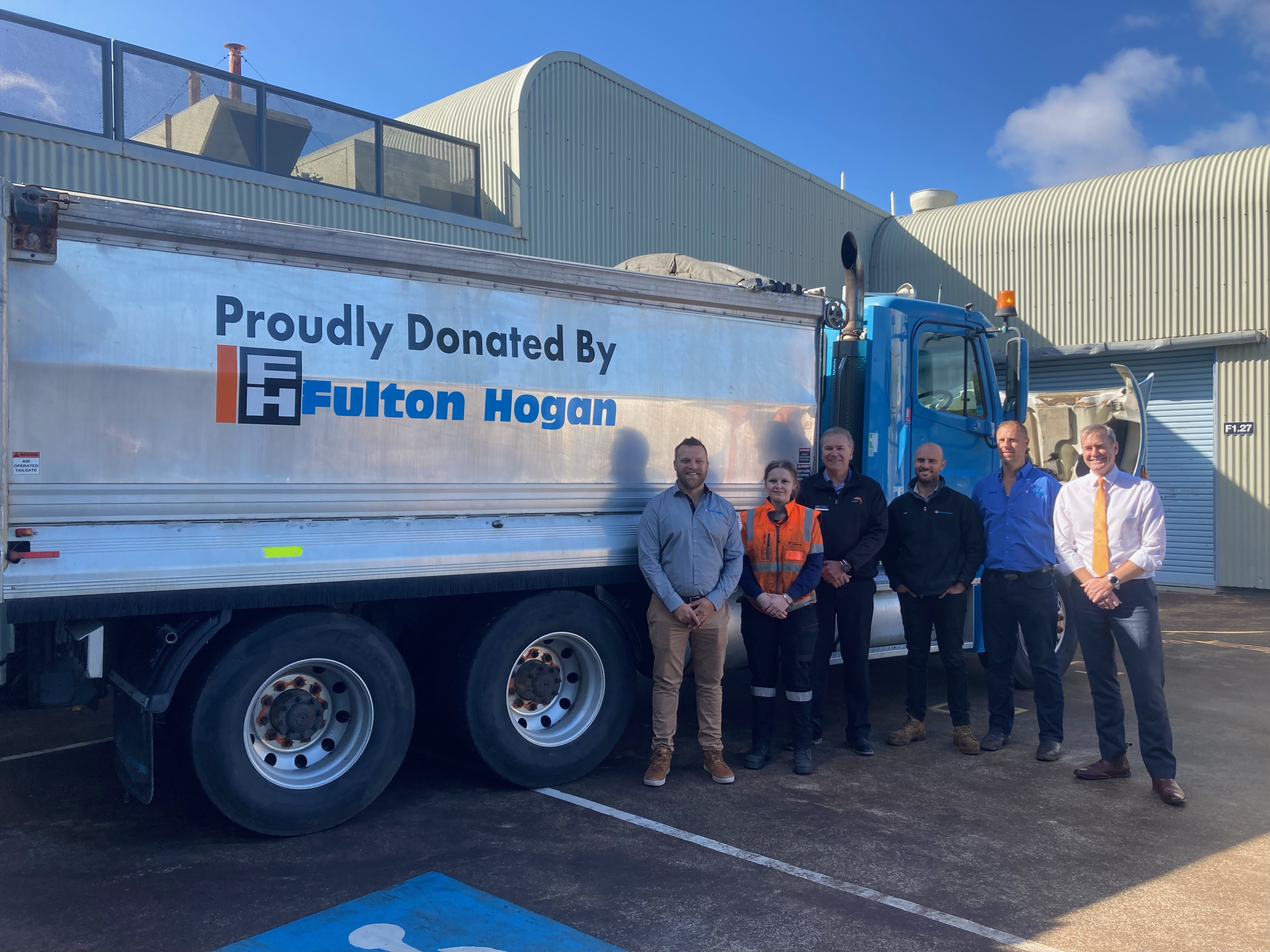 people standing in front of a dump truck for a photo