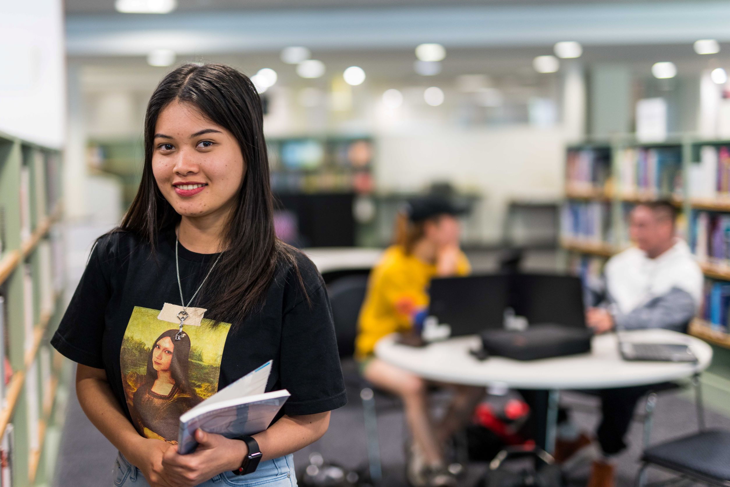 Student Vinya holds a book in the TasTAFE library