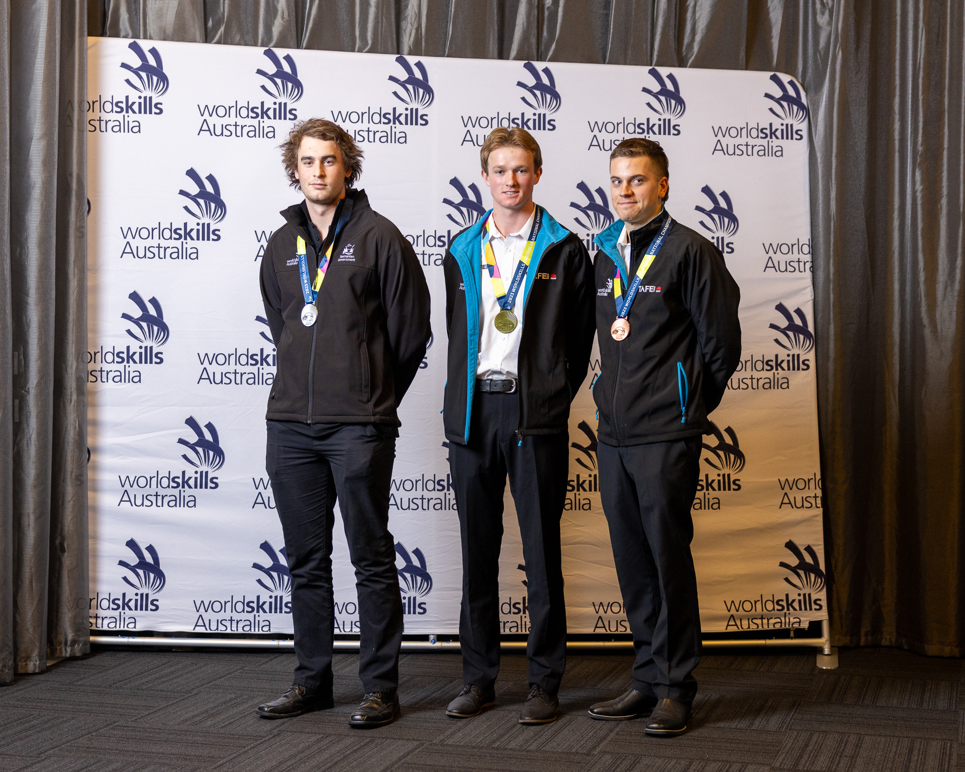 3 men standing for a photo with their medals