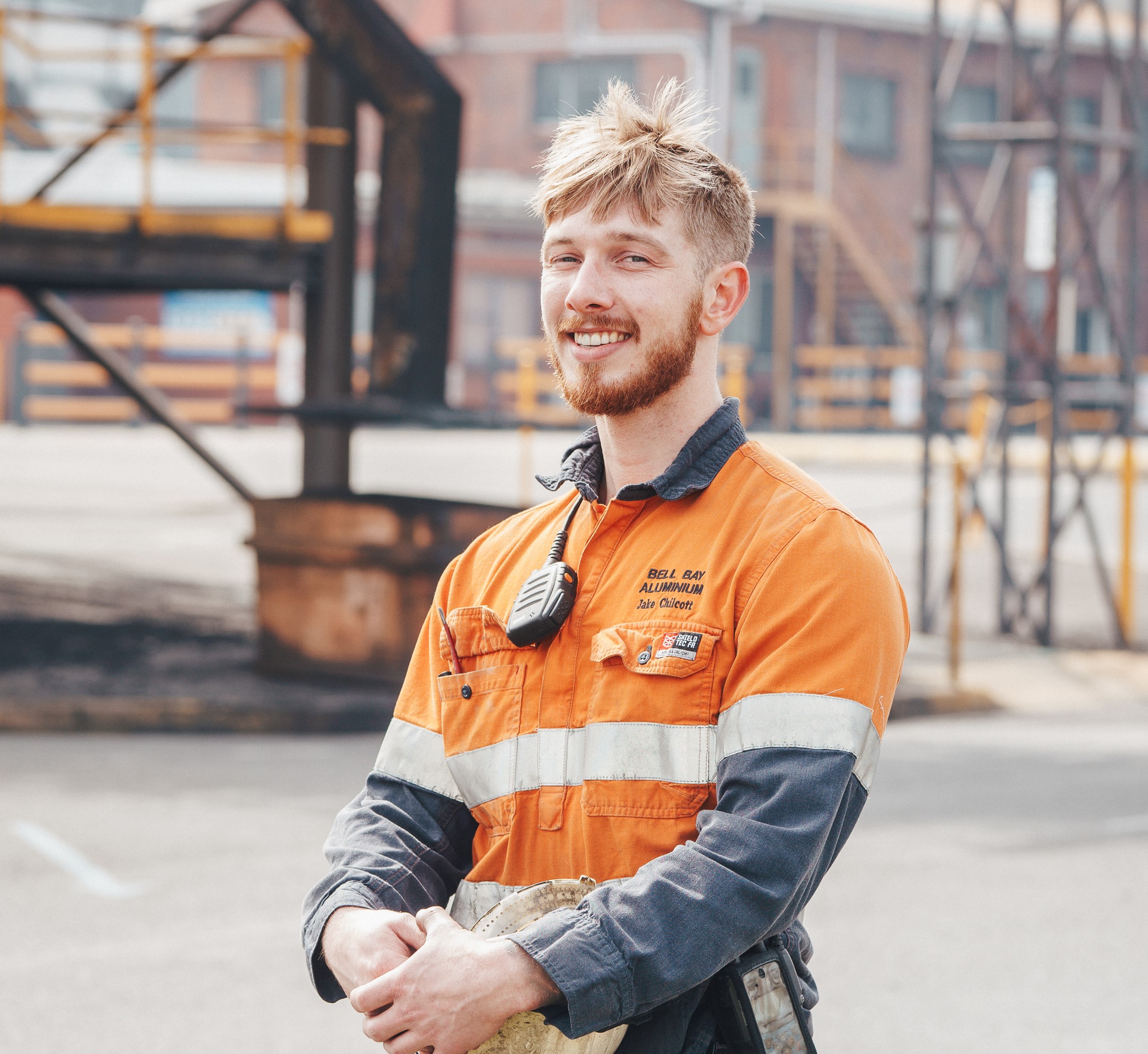 Man standing holding a hard hat in dirty hi-vis work clothes