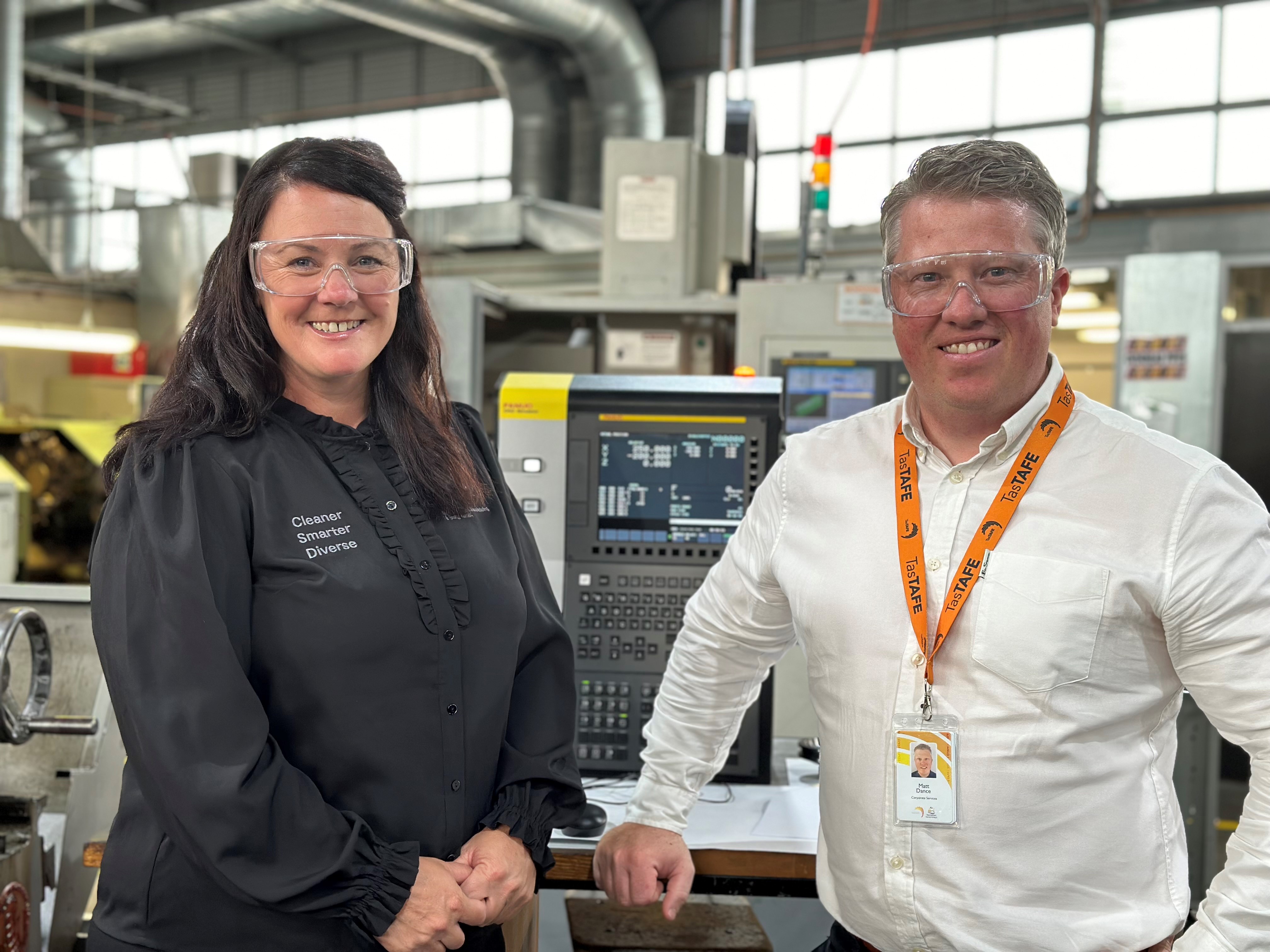 Two people in a metals workshop standing in front of a new simulator