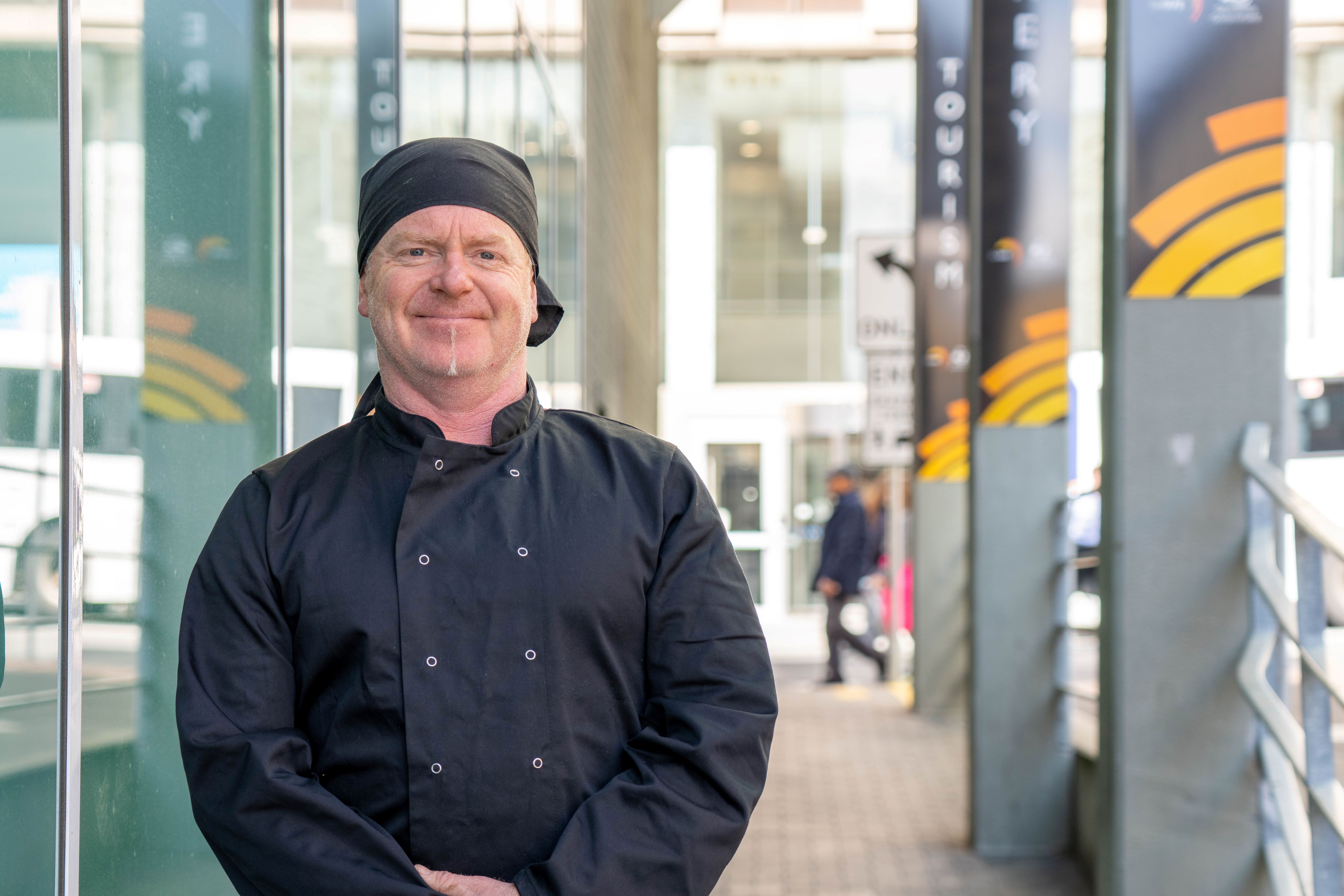 Shayne Jupp wearing black chef clothes in front of TasTAFE Drysdale Campus