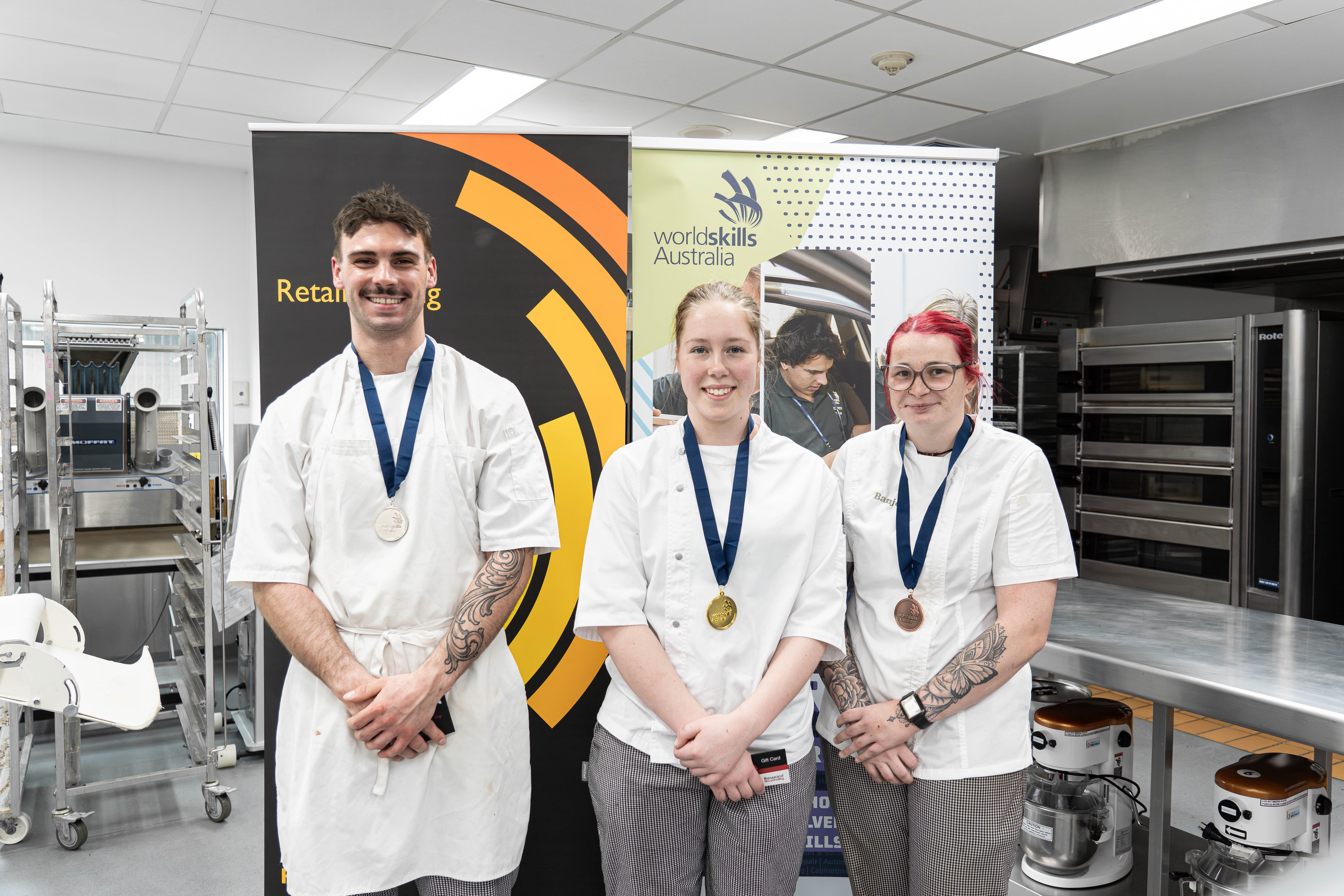 3 people with medals around their necks wearing Chef whites